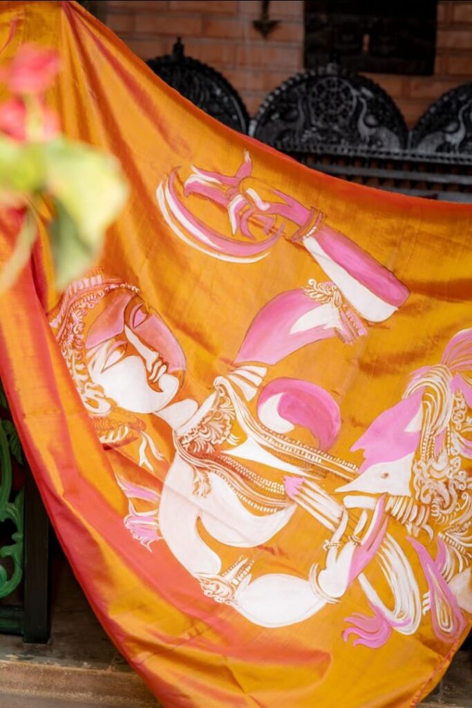 Image shows a hand-painted-wearable art saree in orange colour
